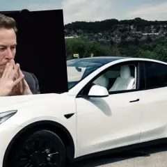Elon Musk, wizjoner stojący za tym, kto produkuje Tesla, zamyślony nad białym Teslą Model Y na tle krajobrazu.