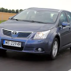 Szary kombi Toyota Avensis na drodze. Kierowca za kierownicą. Jaki silnik wybrać do tego modelu?
